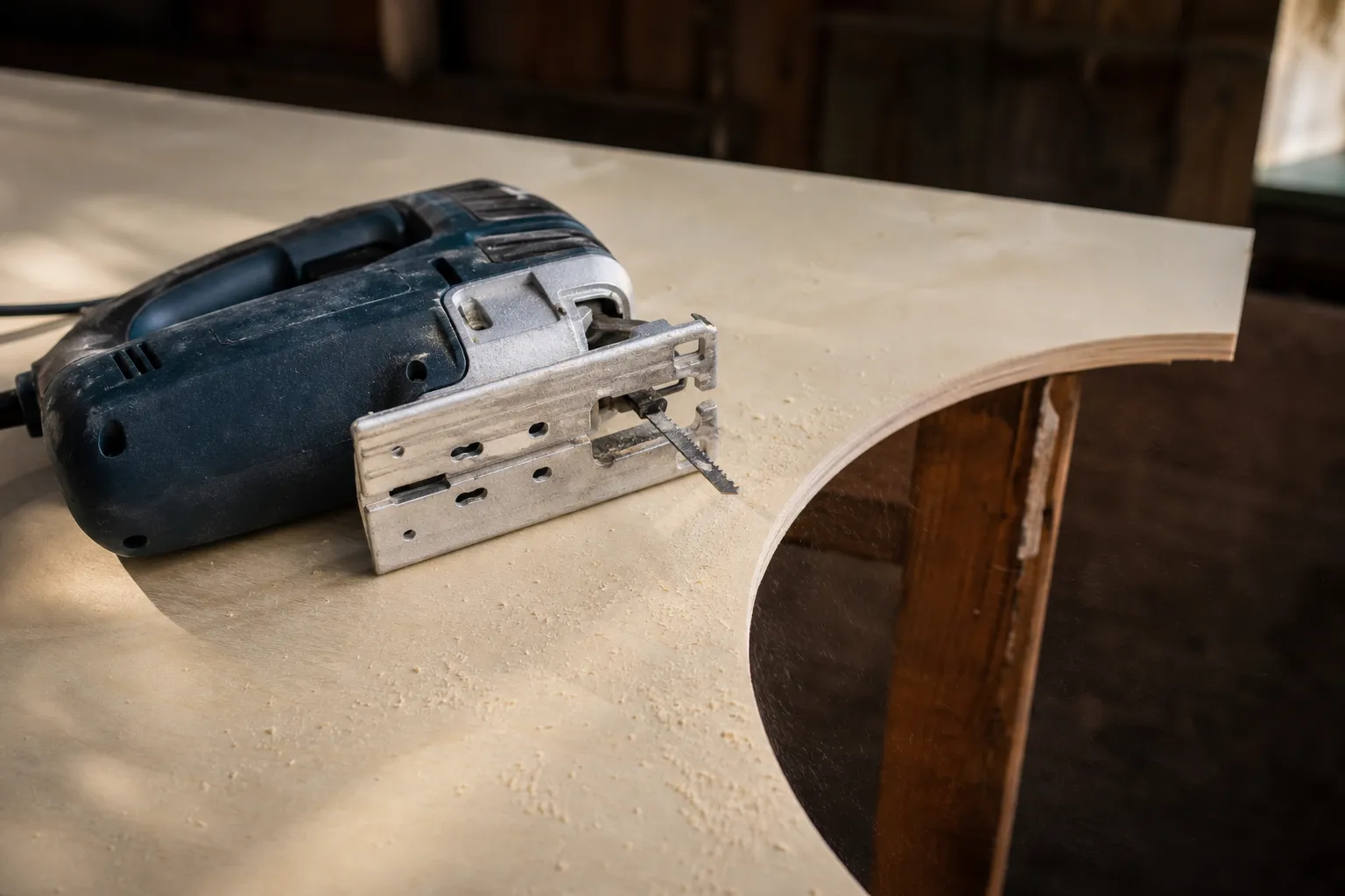 Sticksåg med utbytbart blad liggande på en skiva plywood med ett urskuret hål